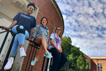 Three students sitting on railing outside school
