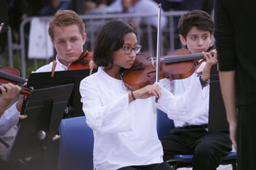 Three orchestra students playing instruments outside