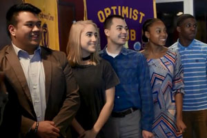 Students standing in front of Optimist Club banner