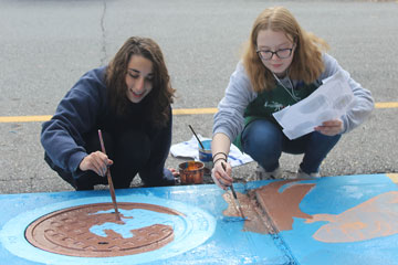Two students painting storm drain