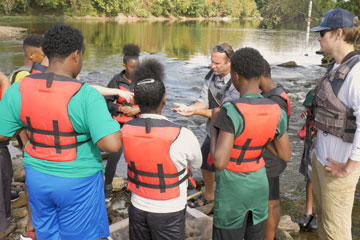 Students in life vests standing by the James River