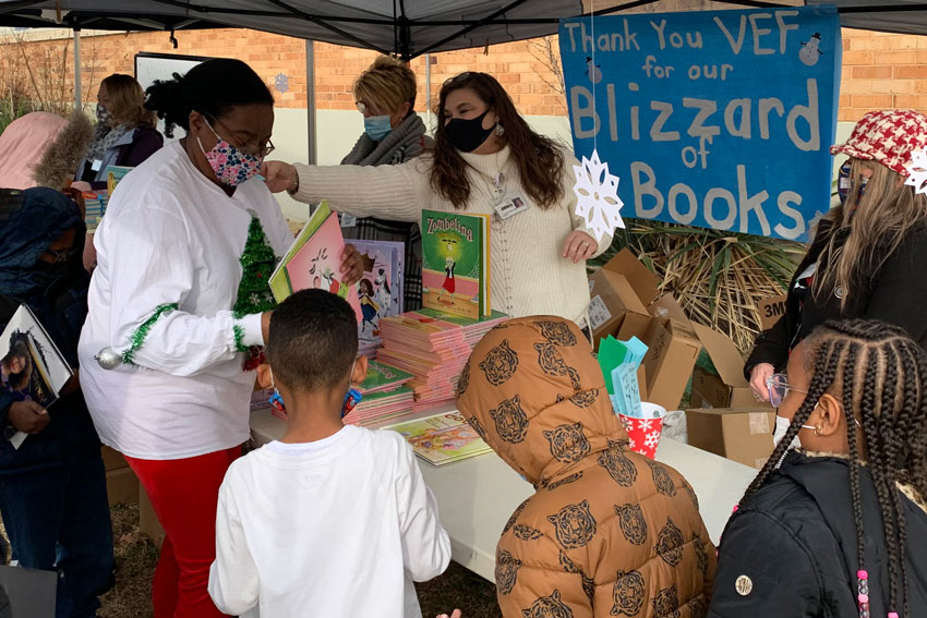 Staff outside school distributing books to students