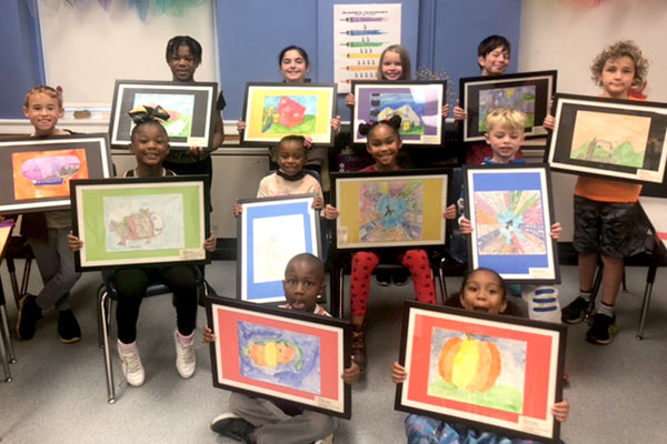 12 students holding framed artwork