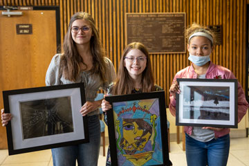 Three students holding artwork
