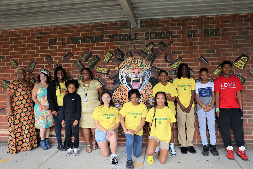 Students, artist and staff standing in front of jaguar mural