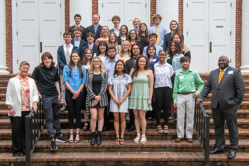Group of senior honors recipients standing on stairs with principals