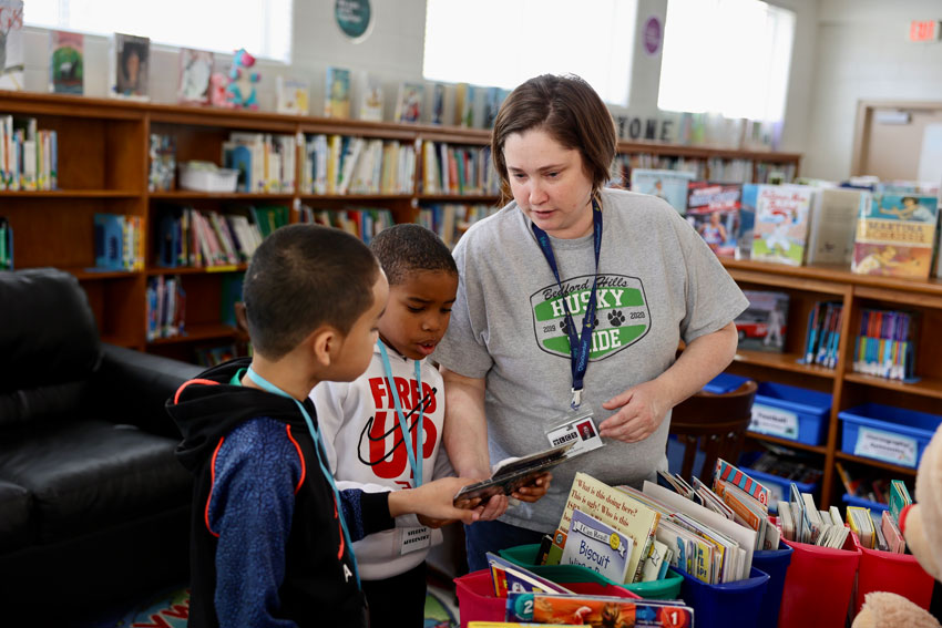 Librarian working with 2 students in library