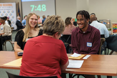 Two students at table smiling during interview