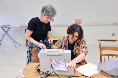 Teacher with student working with sewing machine