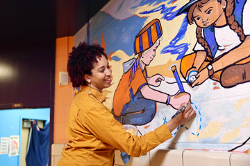 Artist painting mural of little pioneers