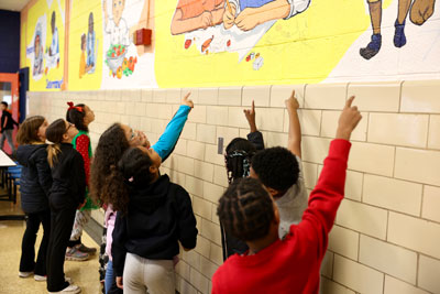 Students pointing at school mural