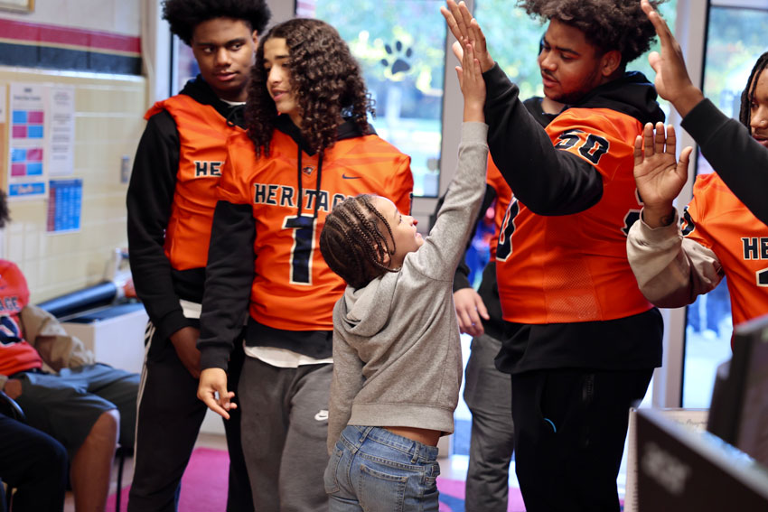 High school football player giving elementary student high 5