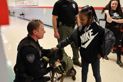 K9 Police officer with student petting dog