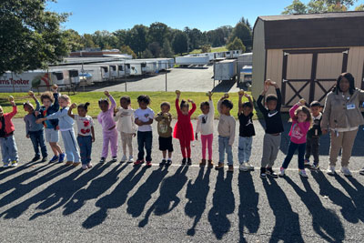 Students lined up outside on blacktop holding apples