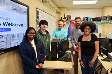 Students, teacher and community partner standing with computer server