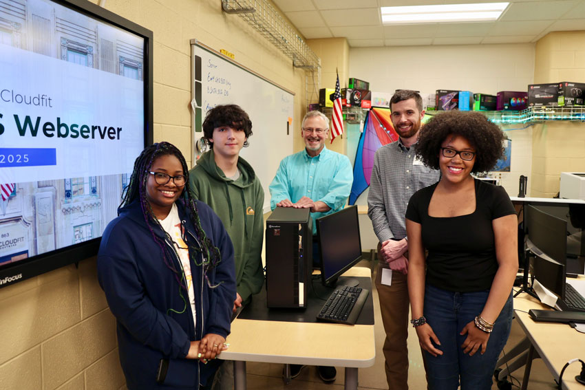 Students, teacher and community partner standing with computer server
