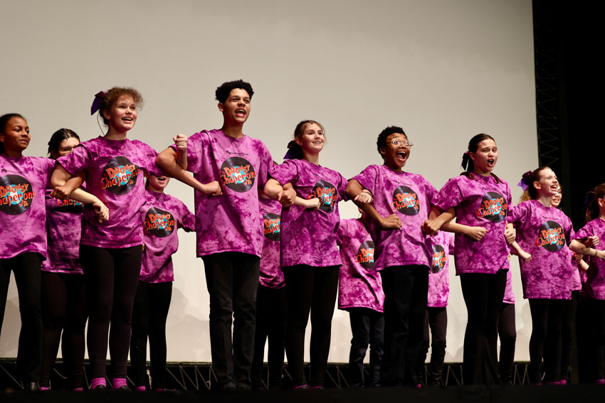 Theatre students in matching shirts signing while interlocking arms