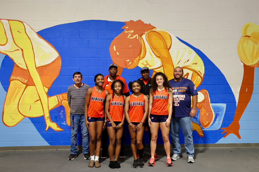 Track team members in front of mural in gym