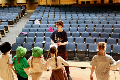 High school student working with elementary students at theatre camp
