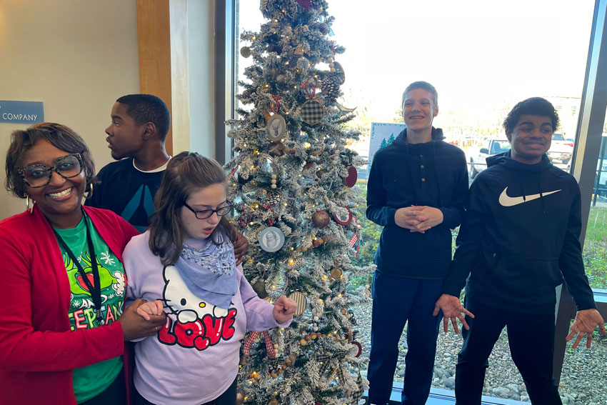 Principal and four students standing around Christmas tree