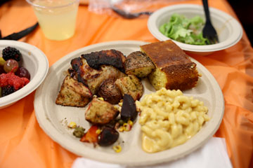 Plate of food with chicken, mac 'n' cheese, cornbread, salad, fruit and drink