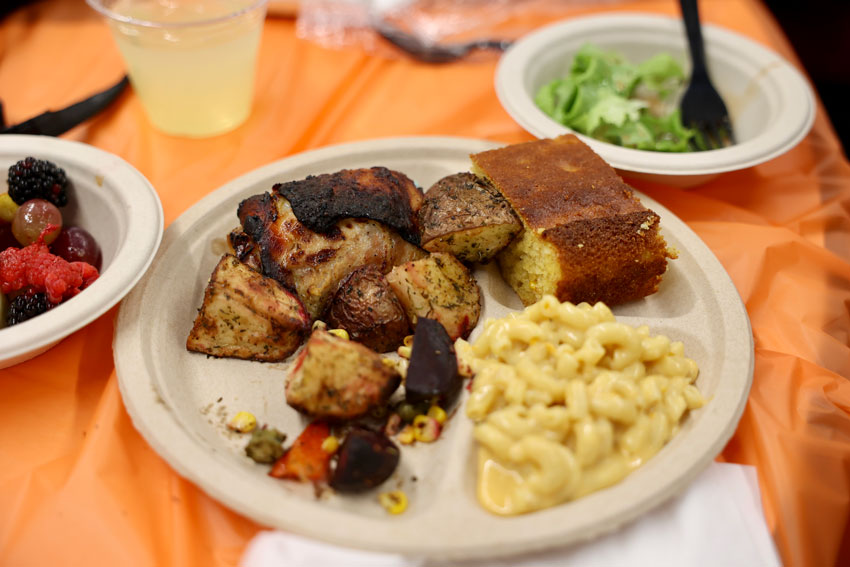 Plate of food with chicken, mac 'n' cheese, cornbread, salad, fruit and drink