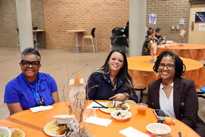 Three school administrators smiling at cafeteria table