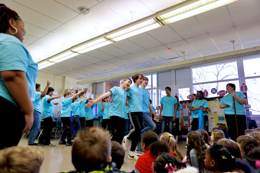 Middle school students performing musical number for elementary students in classroom