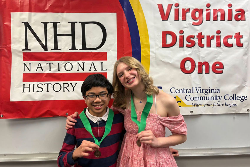 Two students showing medals in front of banner that reads "NHD National History Day Virginia District One Central Virginia Community College"