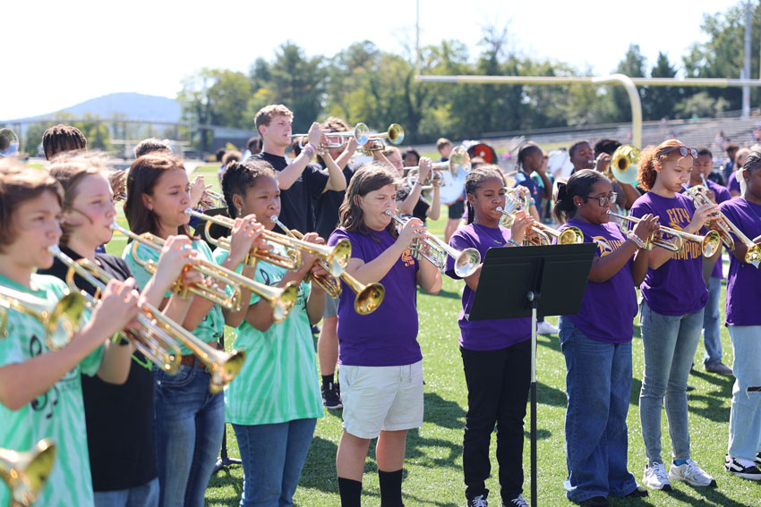 Middle and high school bands on field warming up together