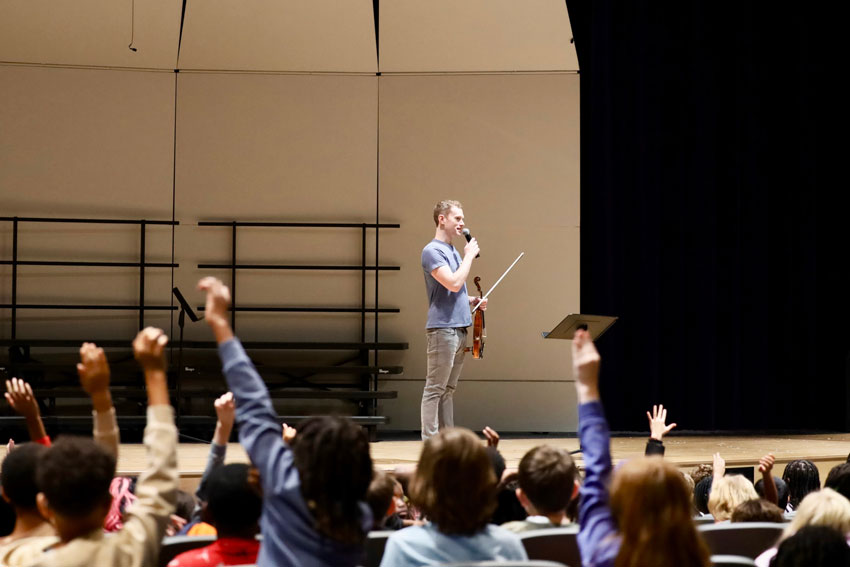 Finn Magill speaking to students in an auditorium