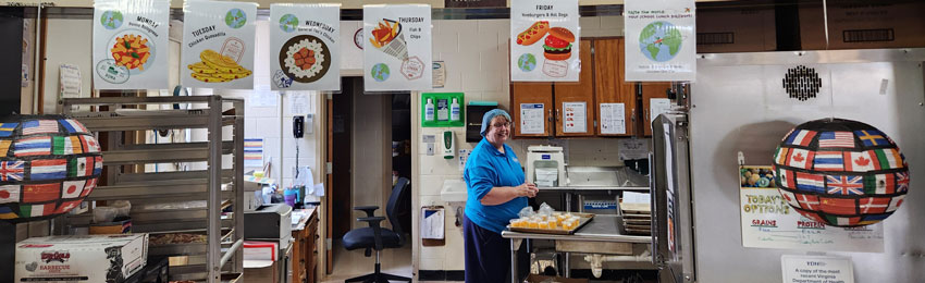 Cafeteria worker in kitchen smiling while preparing food