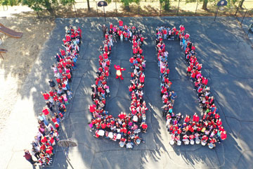 Aerial photo of students and staff arranged to spell "100"