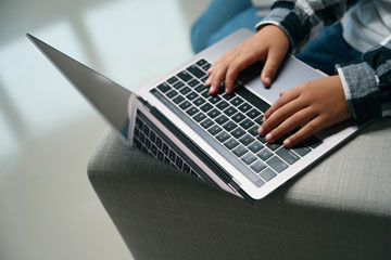 Closeup of child using laptop on couch