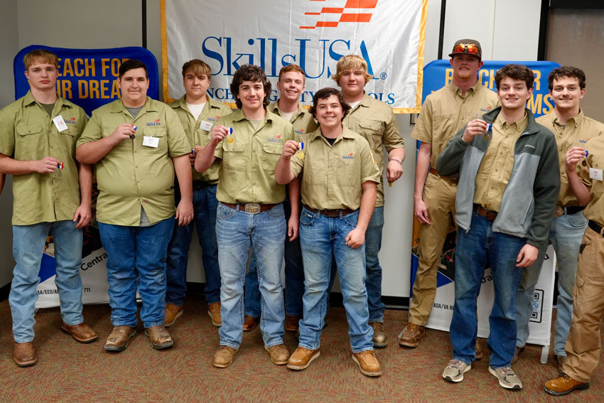 10 construction students in matching shirts holding medals in front of SkillsUSA banner