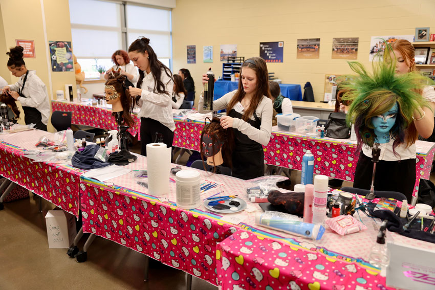 5 cosmetology students styling manikin hair