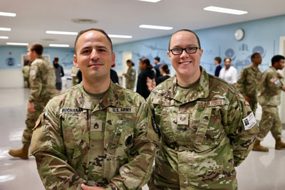 Army and Air Force recruiters in school hallway with students walking in background