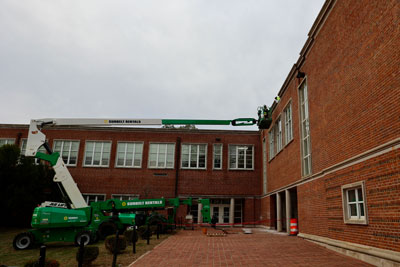 Worker on lift repairing E. C. Glass High exterior