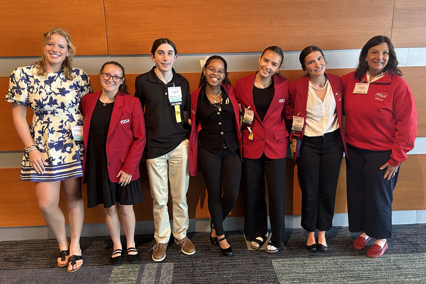 Group of students in matching red FCCLA sports coats with teachers at leadership conference
