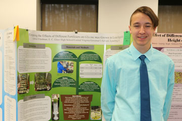 High school student standing in front of science fair display
