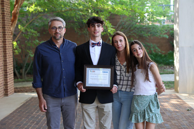 Scholarship recipient holding certificate surrounded by family