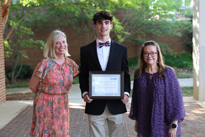 Scholarship recipient holding certificate with Education Foundation director and school administrator