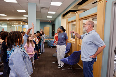 CVCC faculty member speaking in front of a group of elementary students holding up their hands