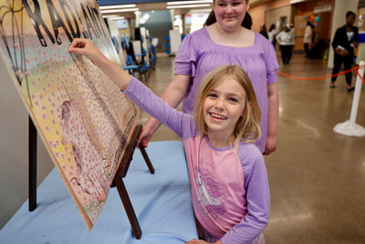 Elementary student placing sticker on Radiant Reader display outside high school auditorium