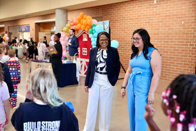Superintendent Somerville-Midgette and Pioneer Theatre Technical Director Taylor Wisskirchen greeting elementary students in lobby area outside of Heritage High School auditorium