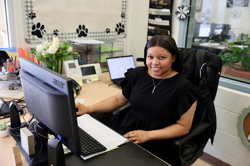 Attendance clerk Mia Reeves seated at her desk