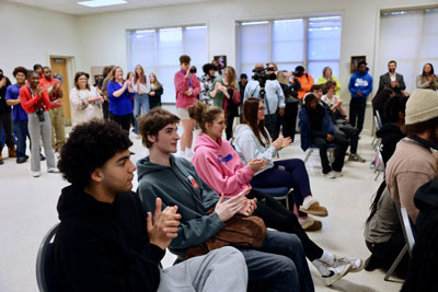 Group of clapping students and staff in lecture hall