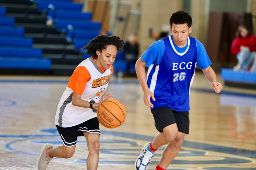 Heritage basketball player dribbling ball near E. C. Glass defender