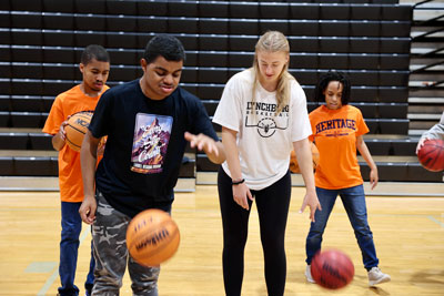 College basketball player working with high school students during clinic