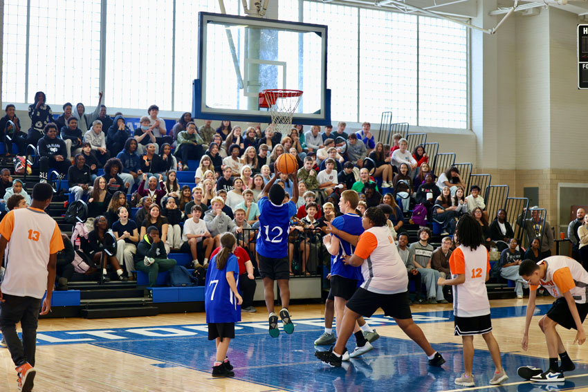 Student shooting basketball with packed crowd in the stands
